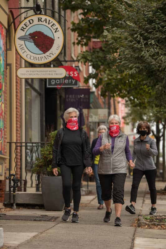 Several women going for a walk down the sidewalk.