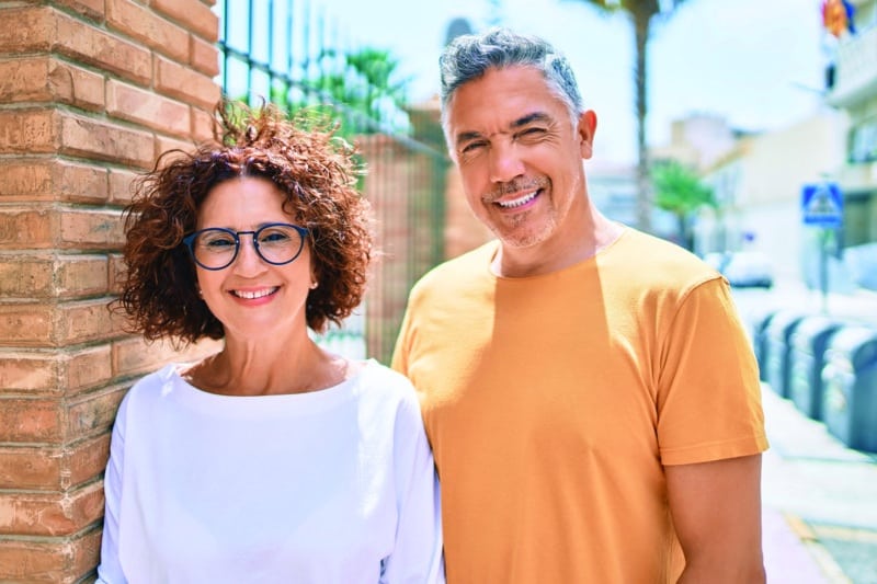 Middle age couple smiling happy leaning on the wall.