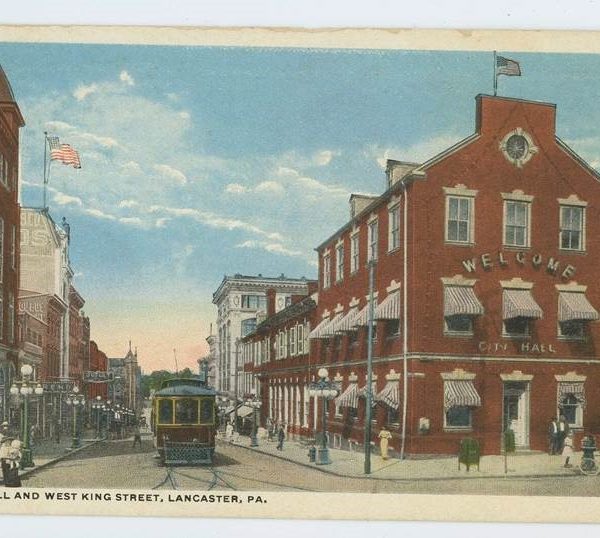 An old photo of a trolly going through a city.