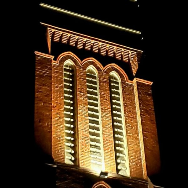 A large, historic, brick tower lit up at night.